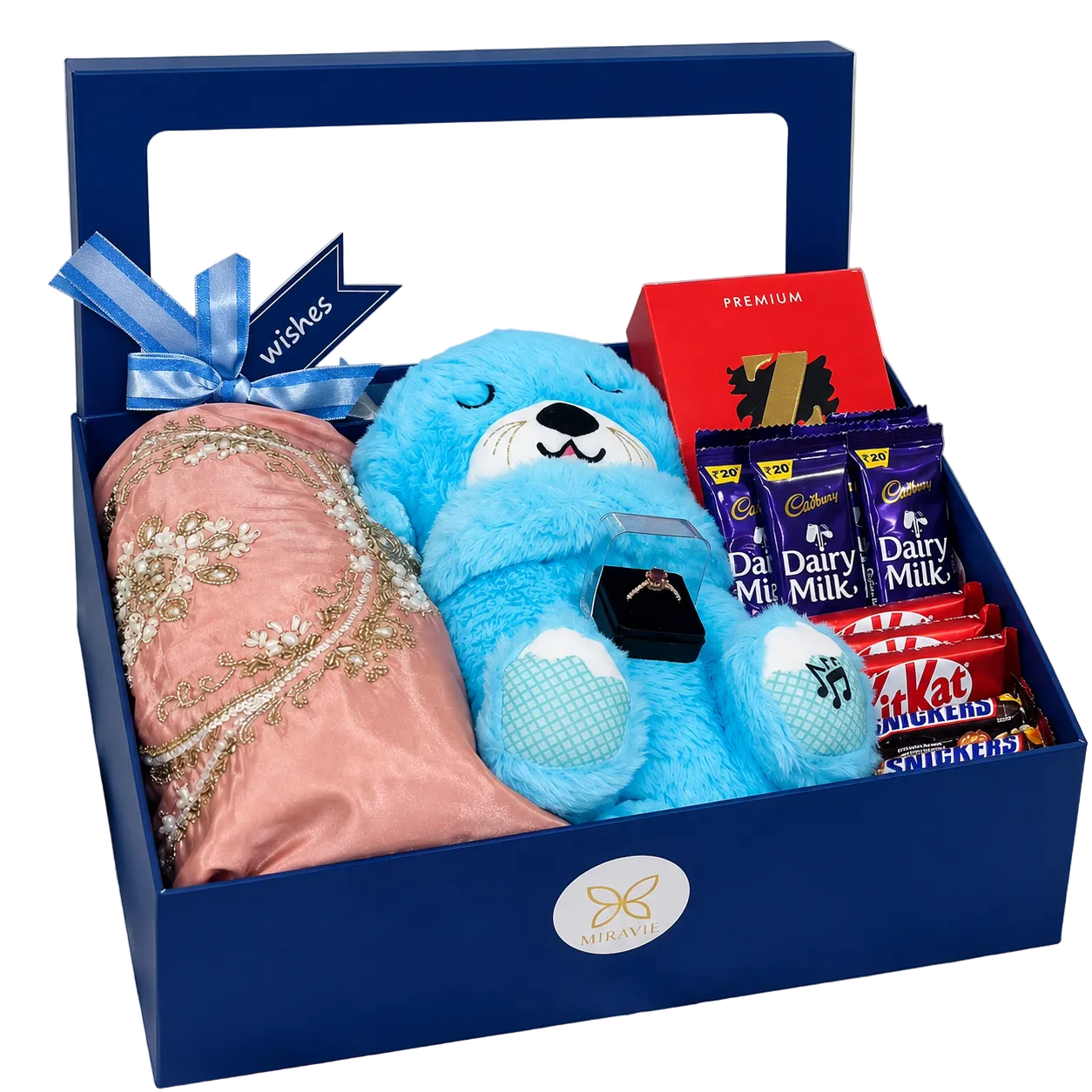 Luxury women’s gift hamper with blue breathing teddy, embroidered pink dress, chocolates, jewellery ring and premium gift box.