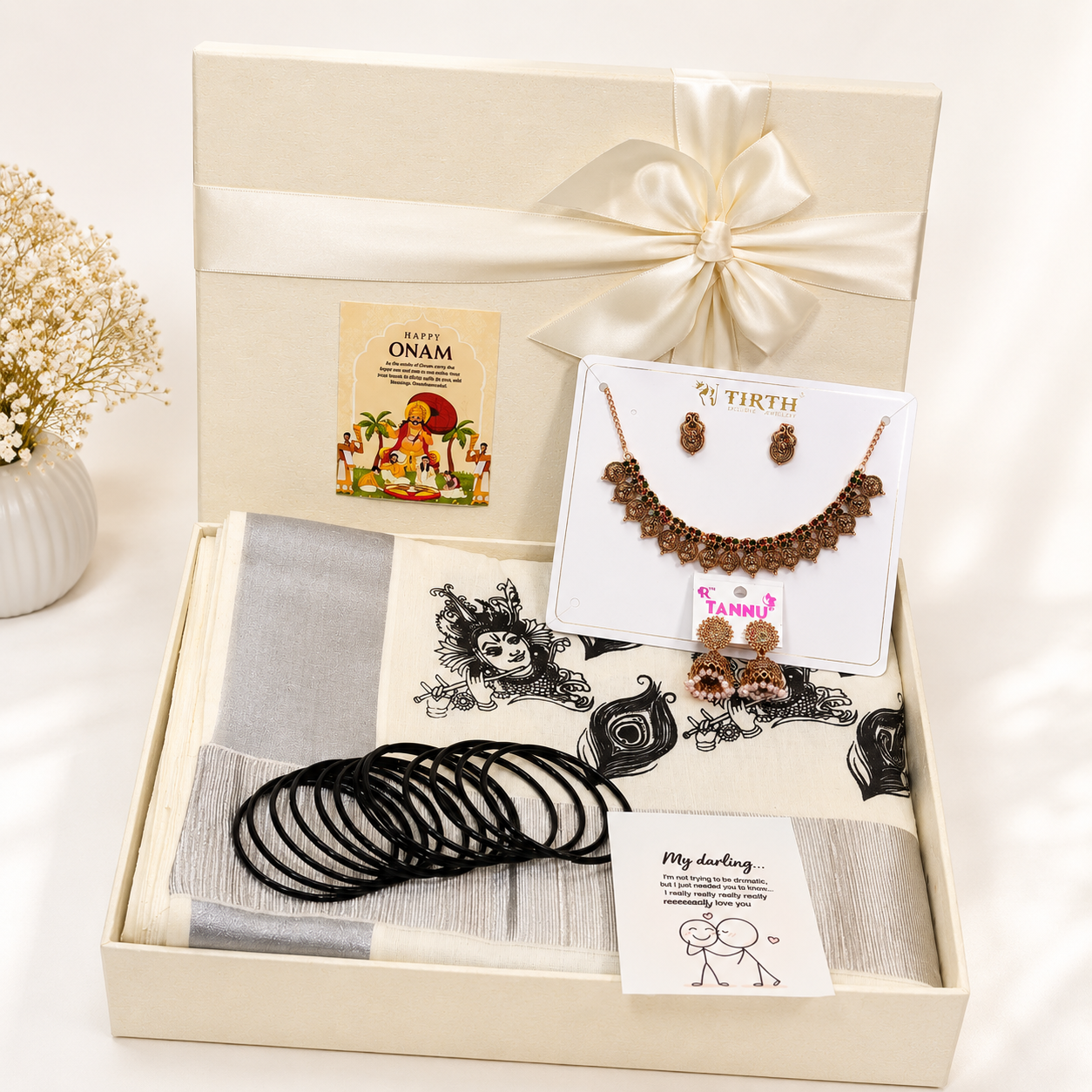 Premium Onam gift hamper featuring a traditional saree, temple-style jewellery set, designer earrings, black bangles, festive greeting card, and luxury ribbon gift box for festive gifting.