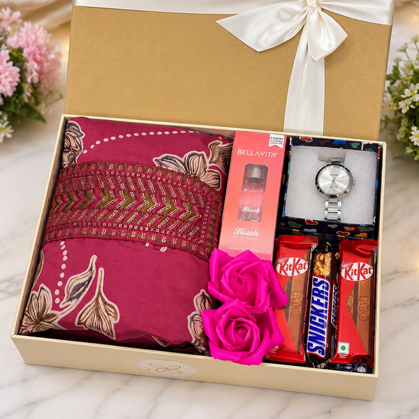 A luxury gift box set on a white marble surface, featuring a deep pink embroidered kurta, a gold watch, KitKat and Snickers snacks, and a pink rose, all presented in a gold box with a white ribbon.