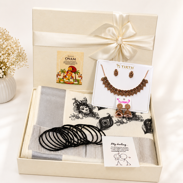 Premium Onam gift hamper featuring a traditional saree, temple-style jewellery set, designer earrings, black bangles, festive greeting card, and luxury ribbon gift box for festive gifting.