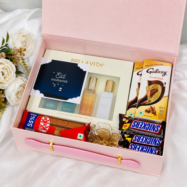 Luxury pink Eid gift hamper box with Bellavita perfume set, KitKat, Snickers, and Galaxy chocolates arranged in premium festive packaging