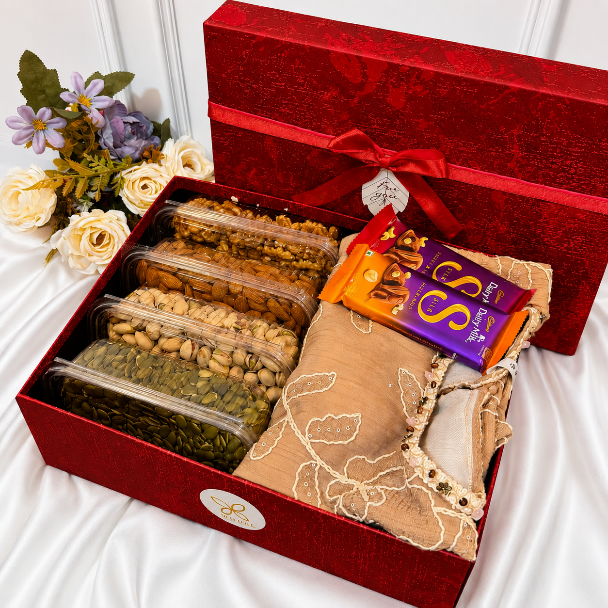 gift hamper with traditional dress, Dairy Milk Silk chocolates, walnuts, almonds, pistachios, pumpkin seeds, and a luxury red gift box.